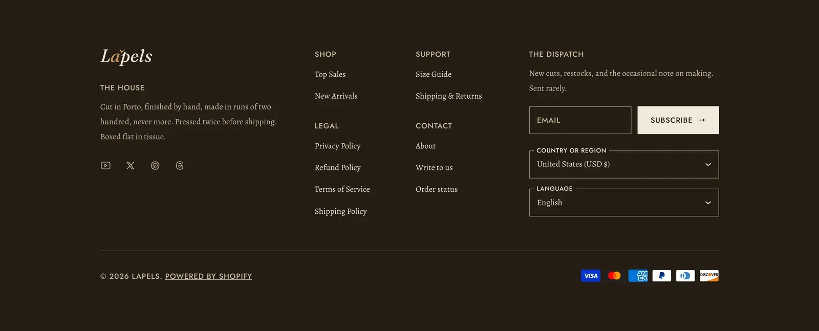 The Lapels footer in the theme's dark scheme: the wordmark over a paragraph headed The House and a row of four social icons in the first column, Shop, Legal, Support and Contact link lists in the middle, and a newsletter block headed The Dispatch with an email field, a Subscribe button and country and language pickers in the third, over a base bar carrying the copyright line and six payment marks.