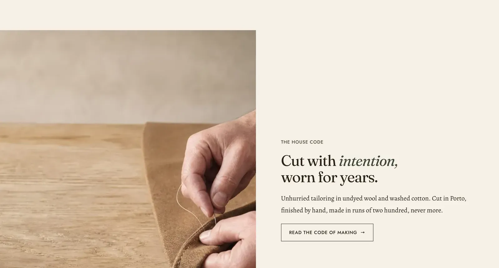 The Lapels Image with text section: a photograph of hands turning back a fold of camel cloth on a workbench filling the left half, and on the right the label "The house code" over the heading "Cut with intention, worn for years." with the second word in italic, a paragraph about undyed wool and washed cotton cut in Porto, and an outlined "Read the code of making" button.