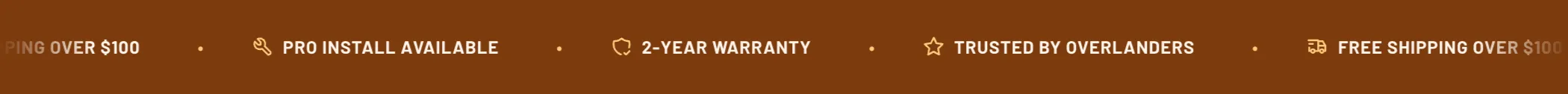 The Torquex marquee — a slim near-black bar of four short messages in bold uppercase type, each led by an orange line icon and separated by orange dots: a truck and "Free shipping over $100", a wrench and "Pro install available", a shield and "2-year warranty", a star and "Trusted by overlanders"