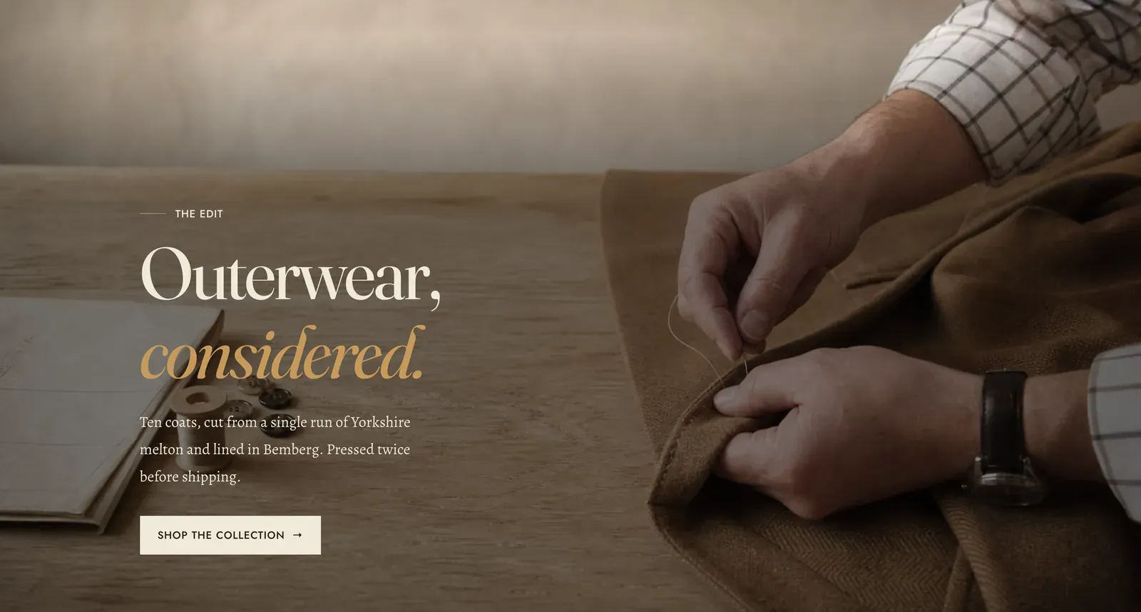 The Lapels Media hero section: a full-bleed photograph of a cutter drawing chalk across dark herringbone cloth on a workbench, washed dark from the bottom, with the label "The edit" above the display heading "Outerwear, considered." in italic, a line of intro text about Yorkshire melton and Bemberg lining, and a "Shop the collection" button.